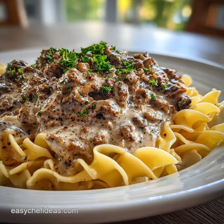 Elegant plate of stroganoff: Tender noodles coated in rich sauce, topped with seasoned beef and a swirl of bright, cool so...