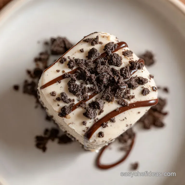 A single square of dark fudge sits elegantly on a white plate, drizzled with white chocolate.
